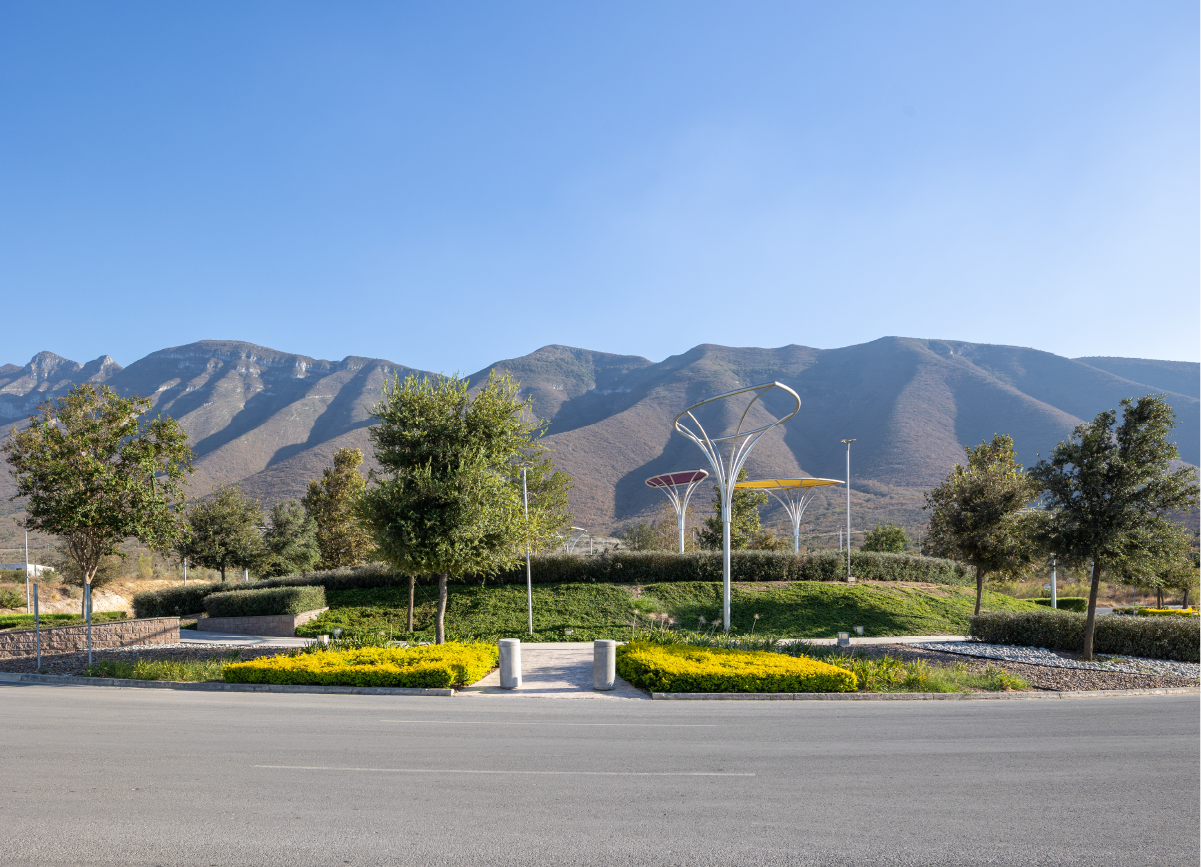 Rotonda con escultura de flores y al fondo cerros